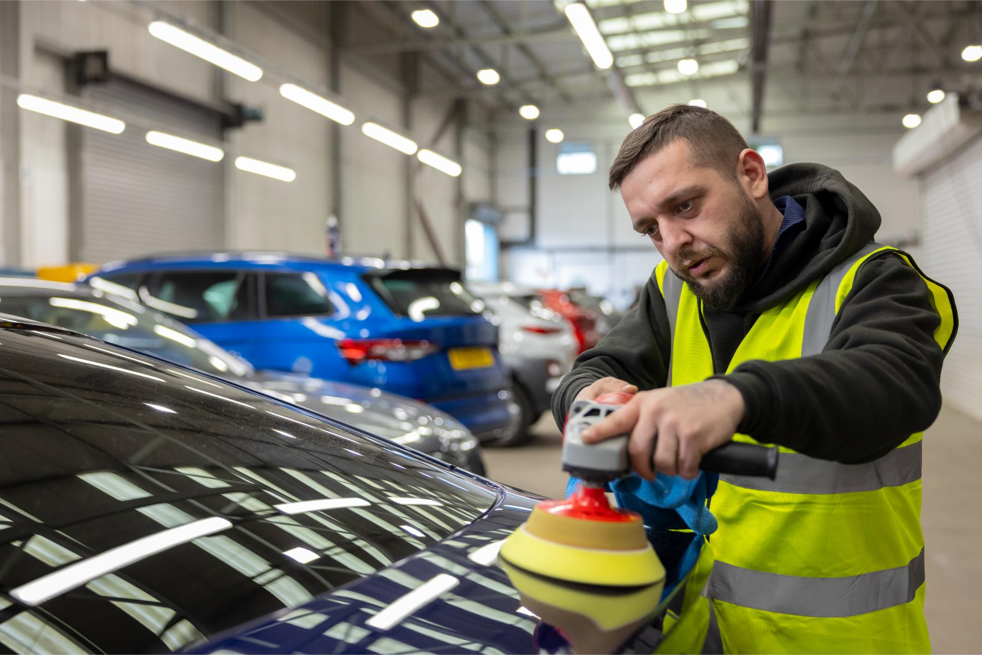 Technician polishing vehicle as part of Cox Automotive fleet preparation and maintenance