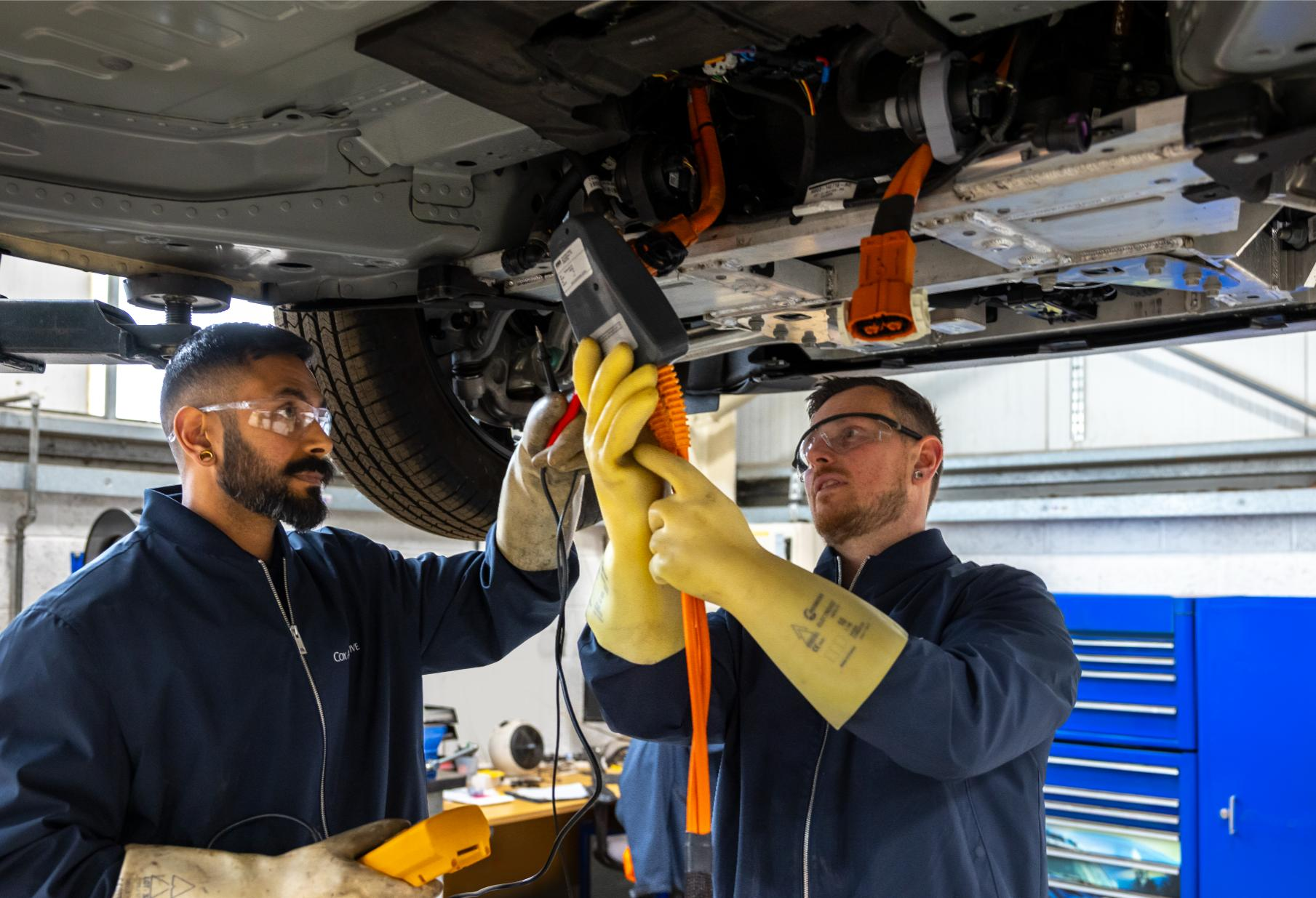 Two Cox Automotive technicians performing EV battery diagnostics for fleet servicing